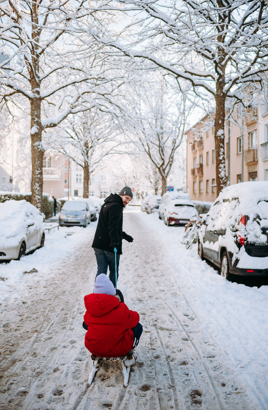 Papa zieht den Schlitten durch die schneebedeckte Straße
