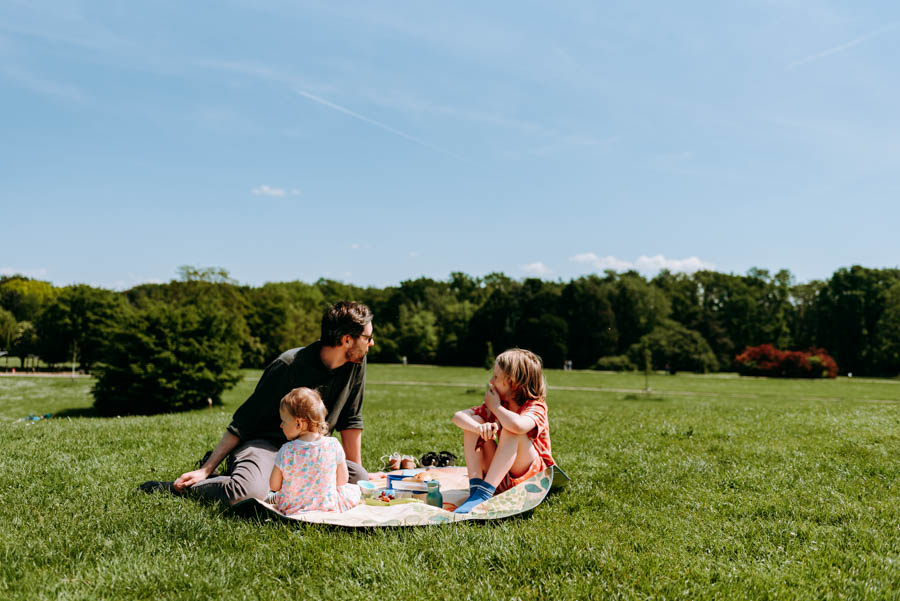 Wit sitzen auf der kleinen runden Picknickdecke auf dem Hügel der großen grünen Wiese.