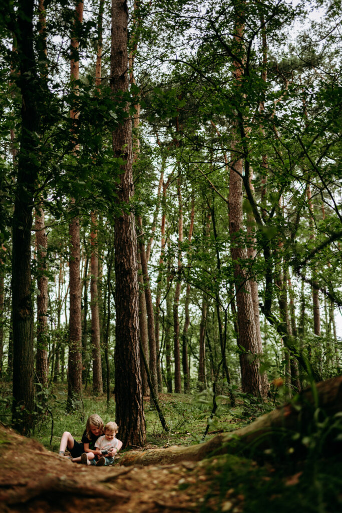 Geschwister im Wald sitzen unter Bäumen