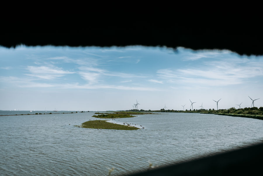 Blick aus dem Tij auf das Haringvliet mit Wasser, Inseln und Windrädern am Horizont