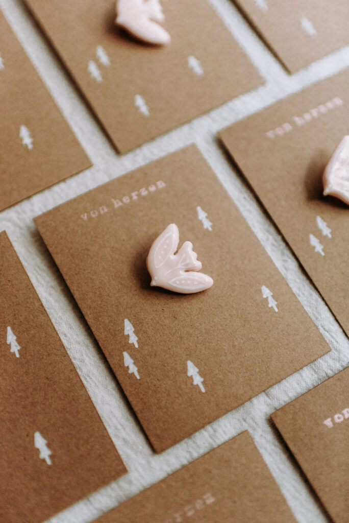 Mehrere braune Karten mit der Aufschrift „von herzen“, jeweils mit einem roséfarbenen Vogel-Anstecker aus Clay (Polymer Clay).