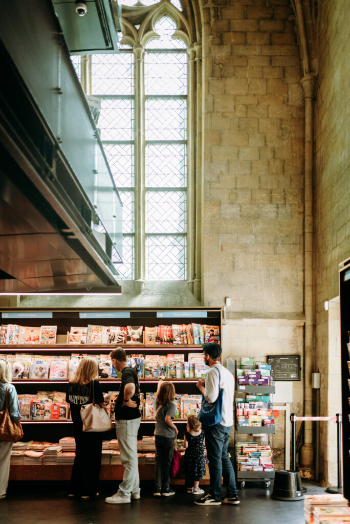 Zeitschriftenstand mit Kindern und Erwachsenen im Innenraum einer Kirche.