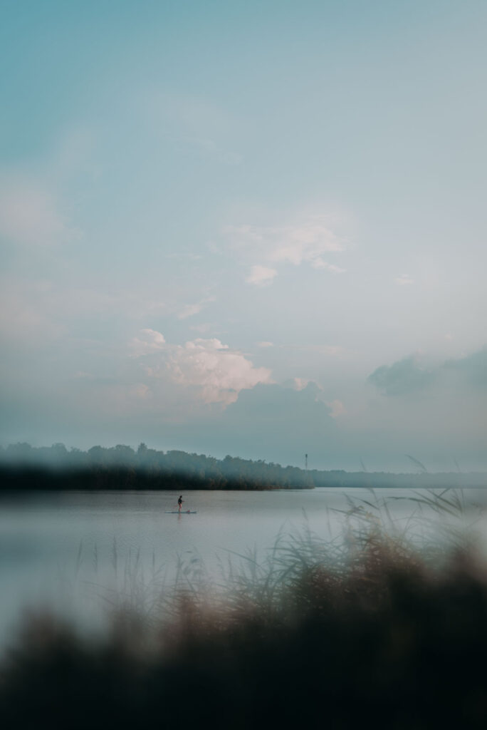 Weite Wasserfläche mit einer einzelnen Person auf dem See beim Standup-Paddling.