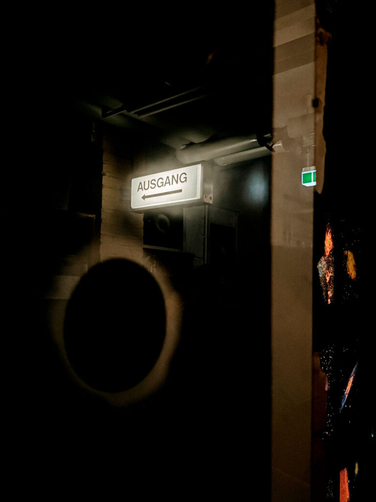 Ausgangsschild hinter Glas mit Spiegelungen und unscharfen Reflexionen.