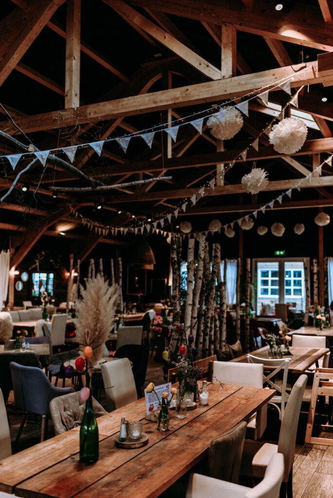 Gemütliche Festscheune mit Holzbalken und gedeckten Tischen auf dem Krewelshof