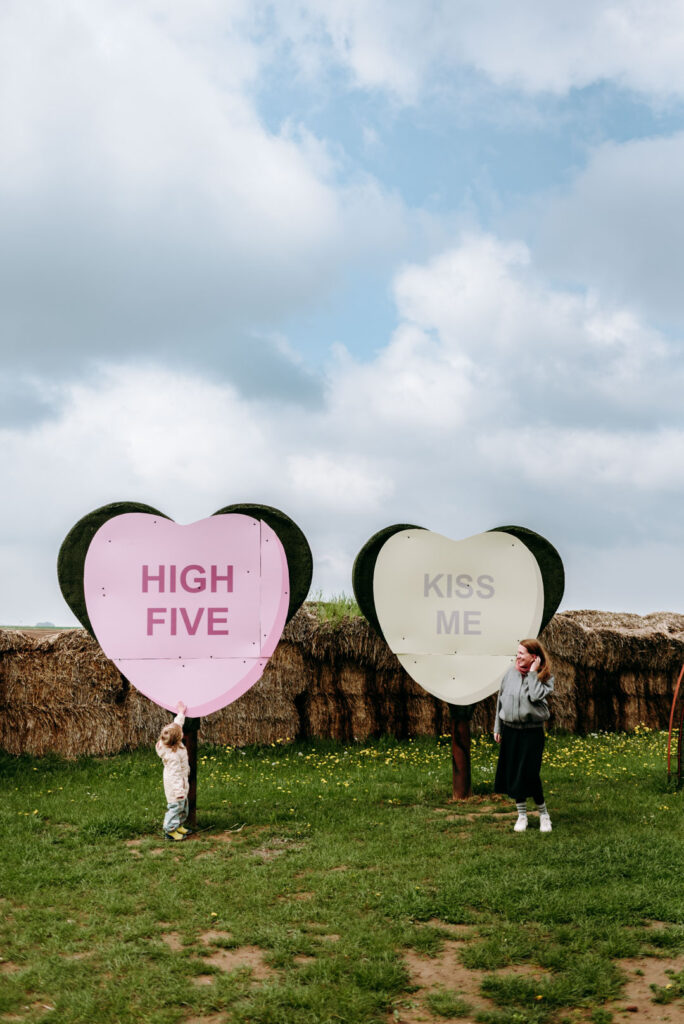 Zwei große Herzschilder mit den Aufschriften „High Five“ und „Kiss Me“