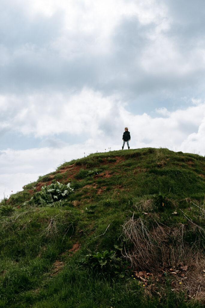 Kind steht auf einem begrünten Hügel auf dem Gelände des Krewelshofs
