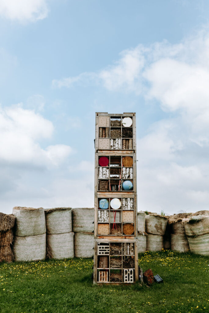 Hohes Insektenhotel vor Strohballen auf dem Gelände des Krewelshofs