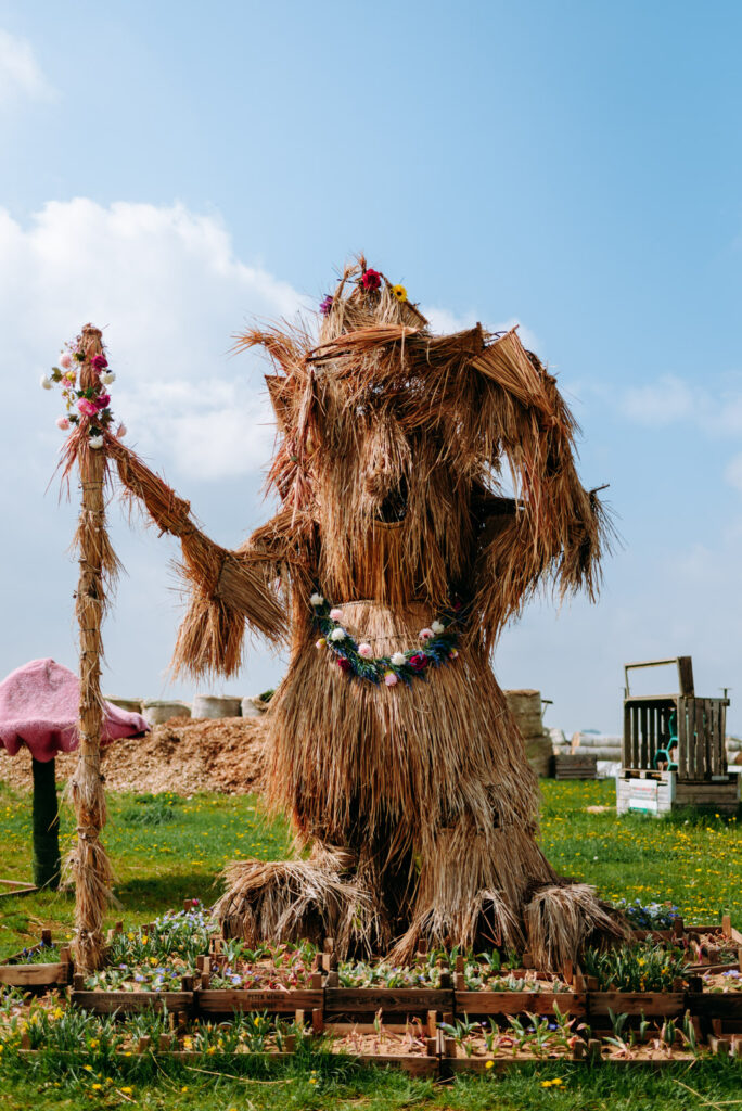 Große Strohfigur mit Blumenkranz als Dekoration auf dem Krewelshof