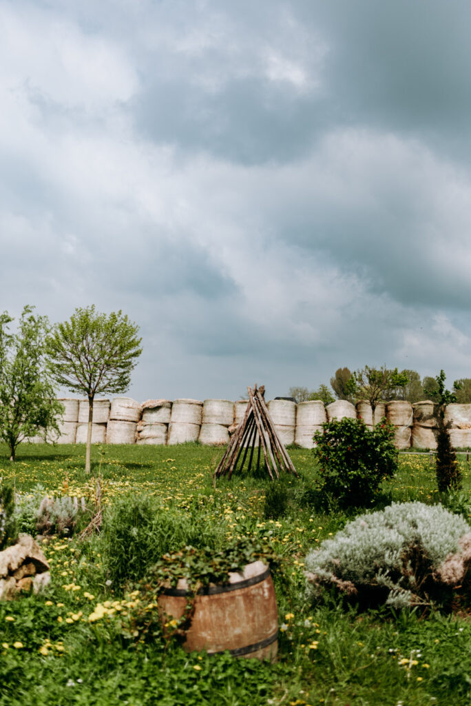 Frühlingswiese mit Strohballen, Tipi und dunklen Wolken auf dem Krewelshof